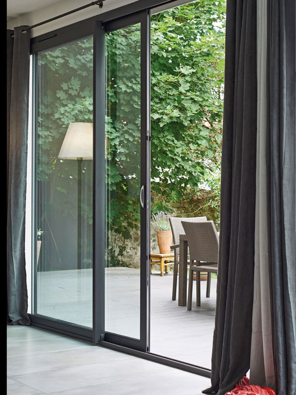 Baie-vitrée en aluminium grise donnant sur une terrasse.